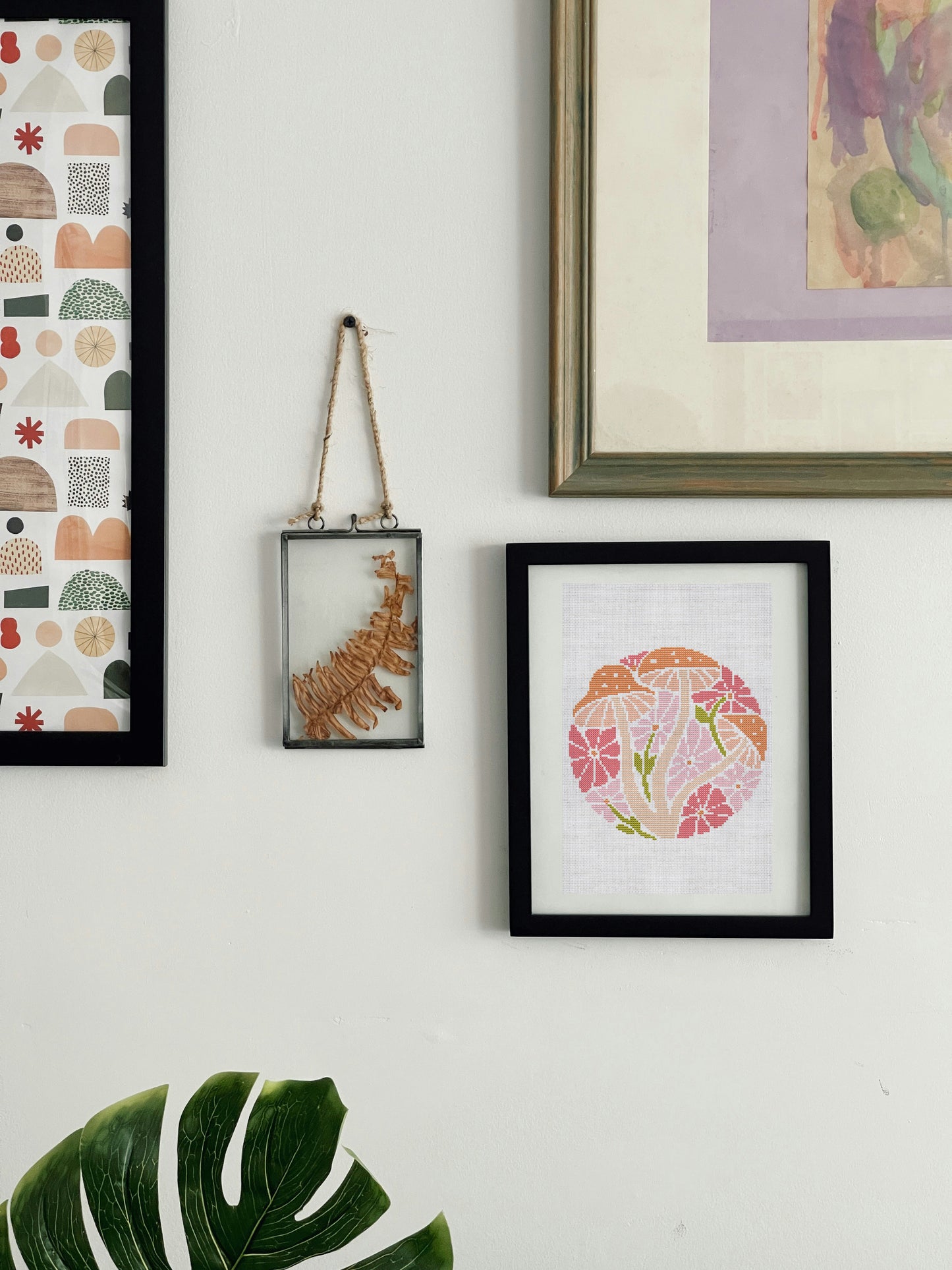 Wall with framed artwork including a floral design, abstract patterns, and a textured piece.