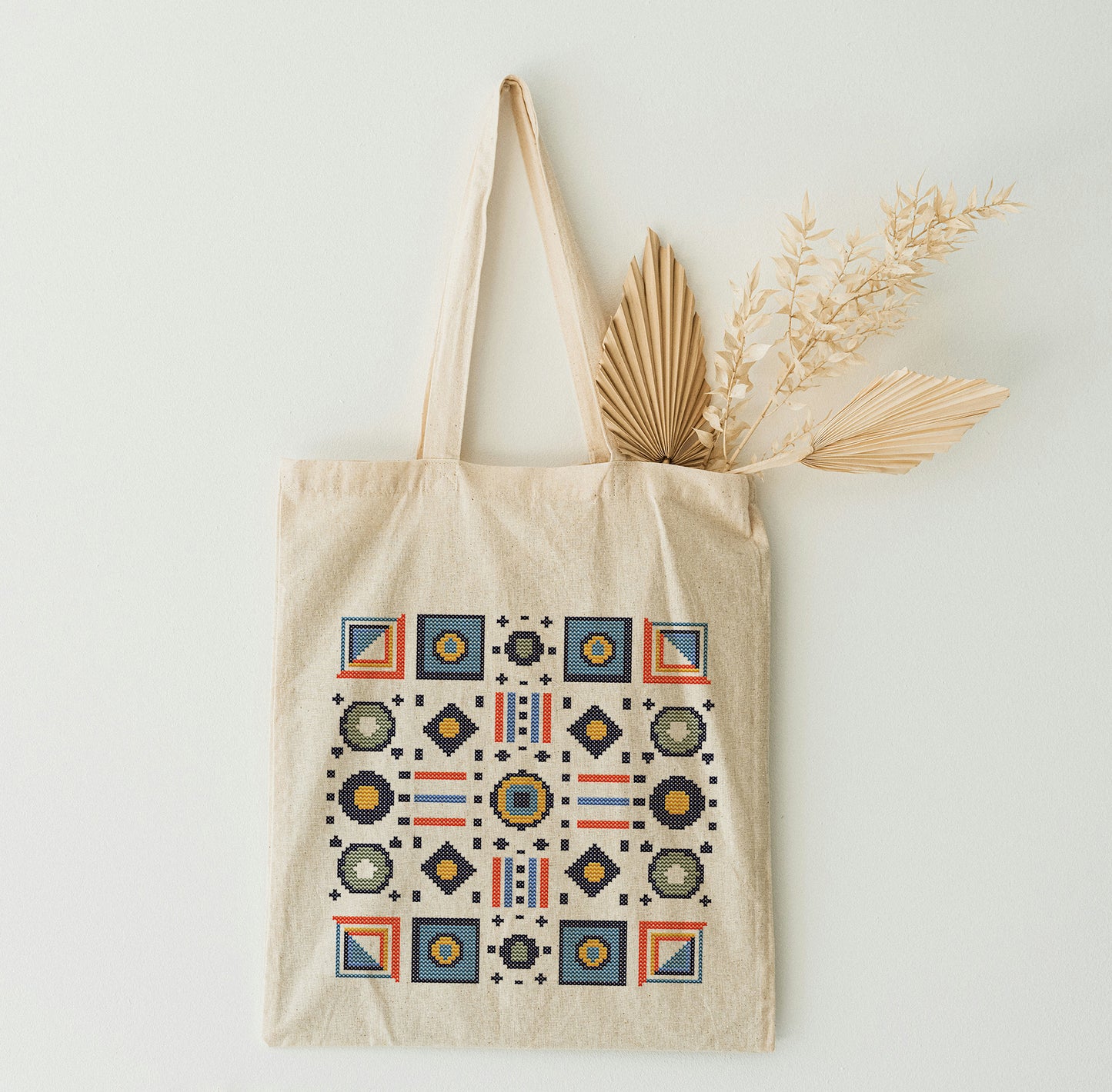 Beige tote bag with mosaic design on a white wall