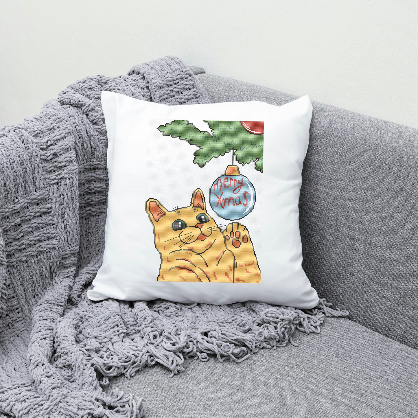 Decorative pillow with a cat and Christmas tree design on a gray couch.
