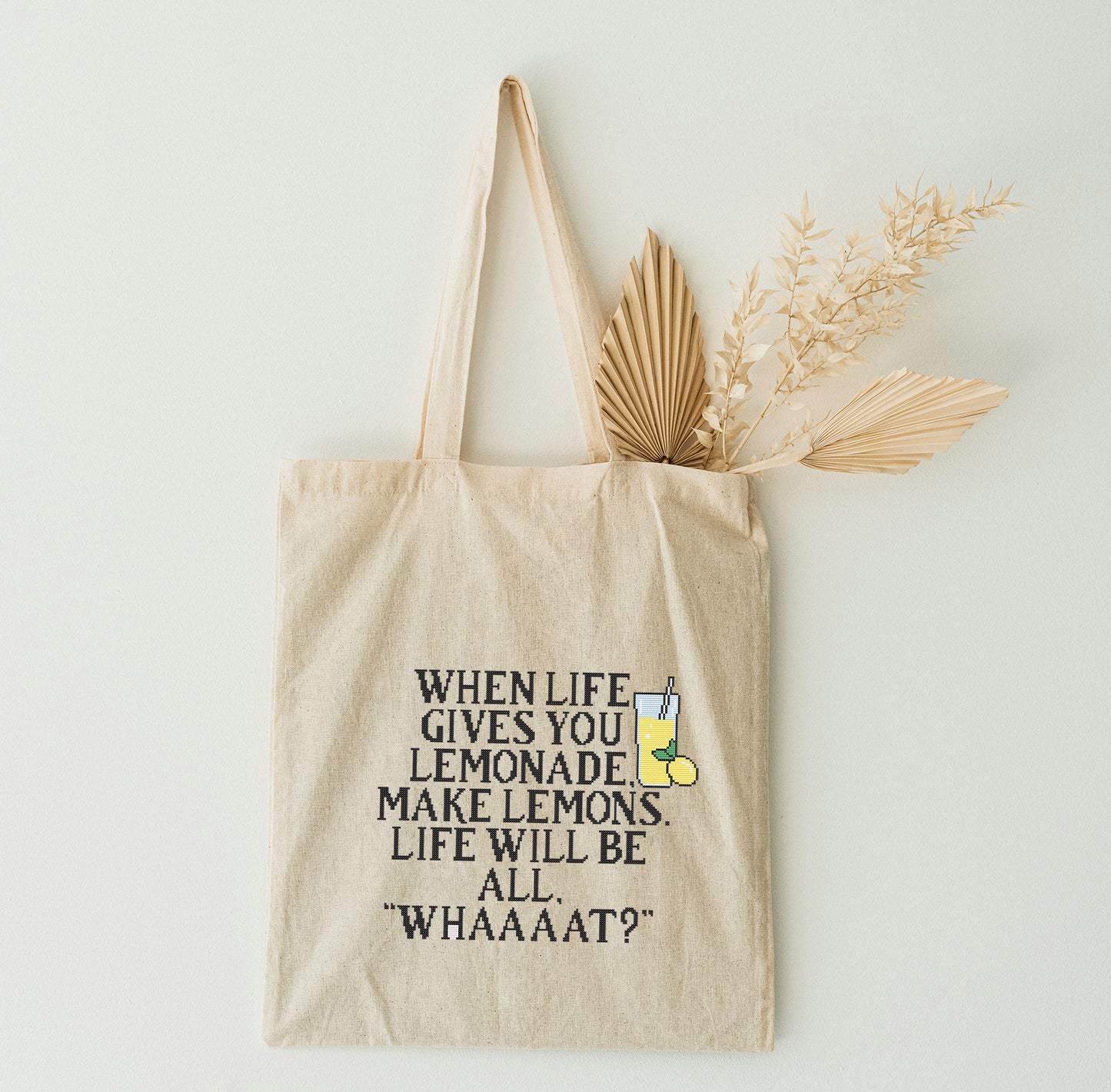 Beige tote bag with humorous text design on a white wall