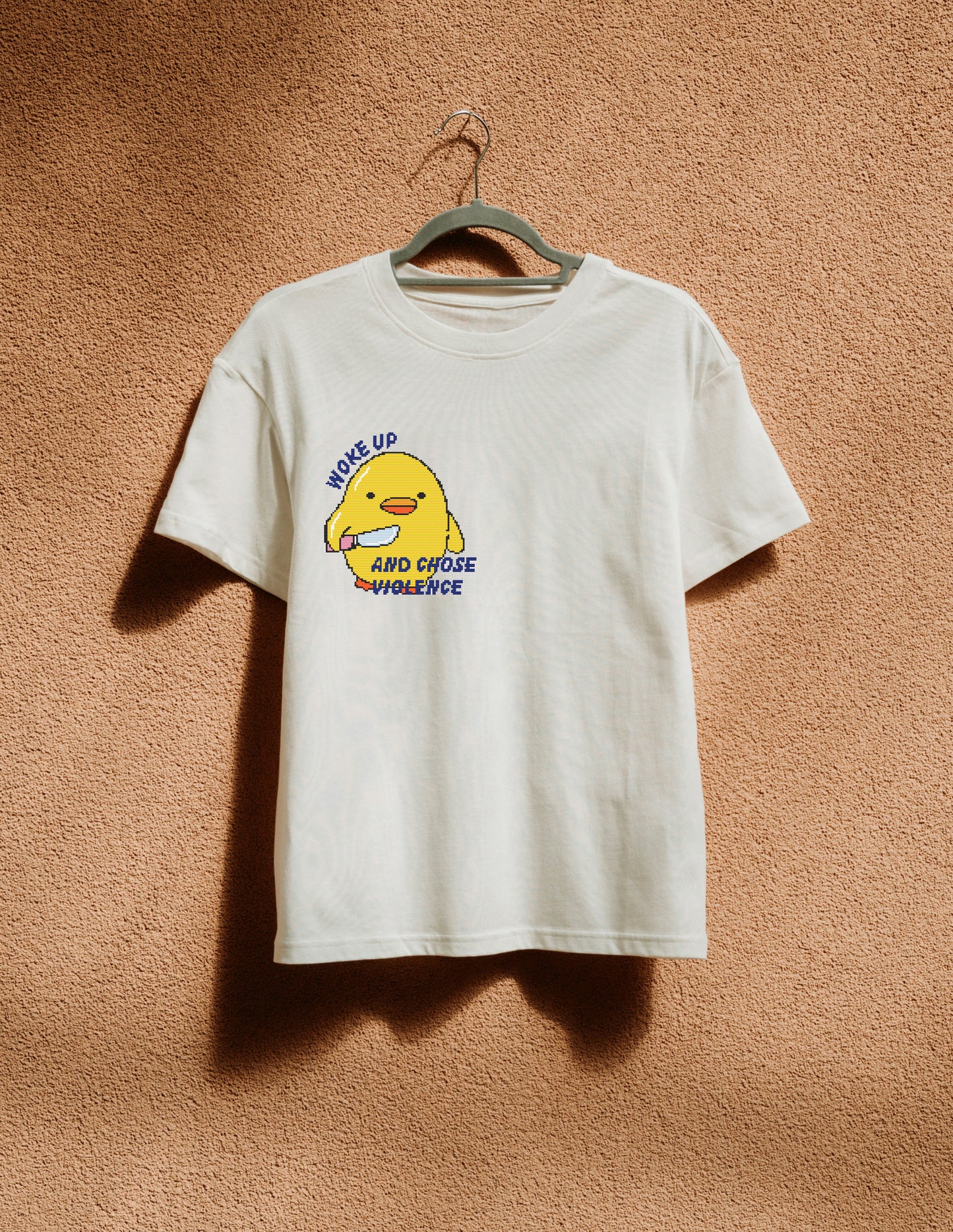 White t-shirt with a yellow character graphic and text on a brown textured background