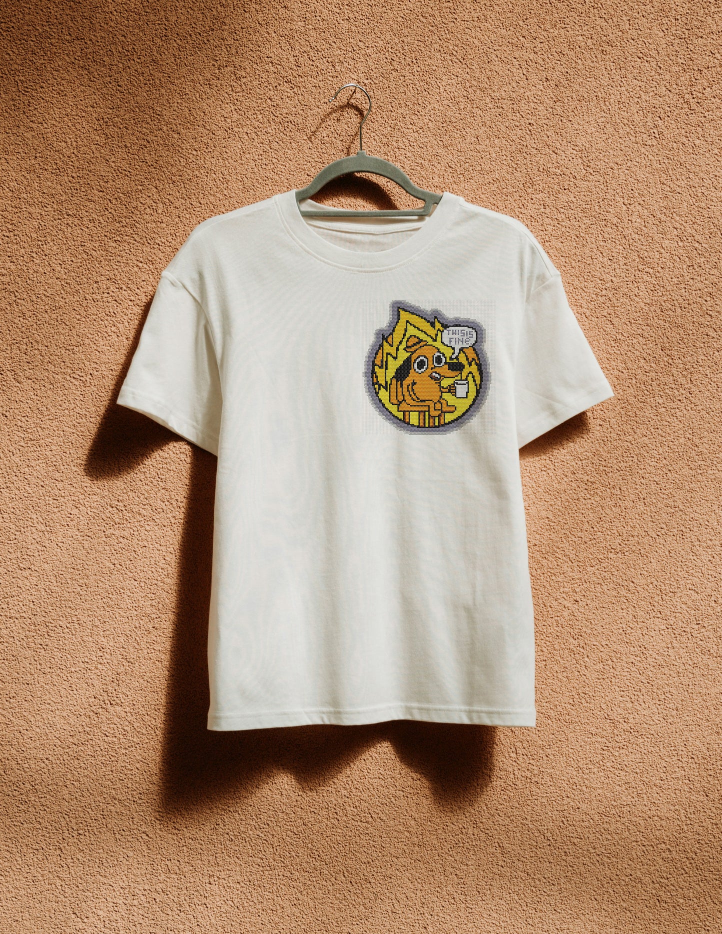 White t-shirt with a colorful graphic on a hanger against a brown textured wall