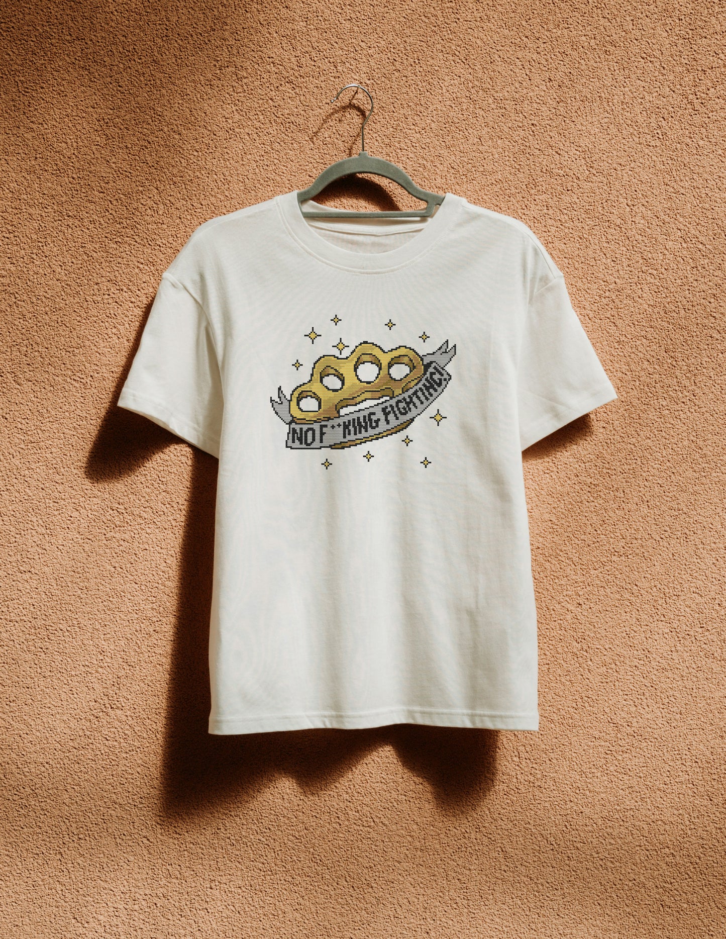 White t-shirt with logo print hanging on the beige wall