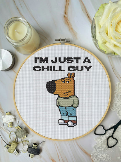 Cross-stitched design of a cartoon character with 'I'm just a chill guy' text on a marble surface.