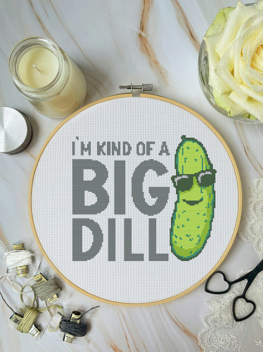 Cross-stitched hoop with a pickle design and text 'I'm kind of a big dill' on a marble surface.