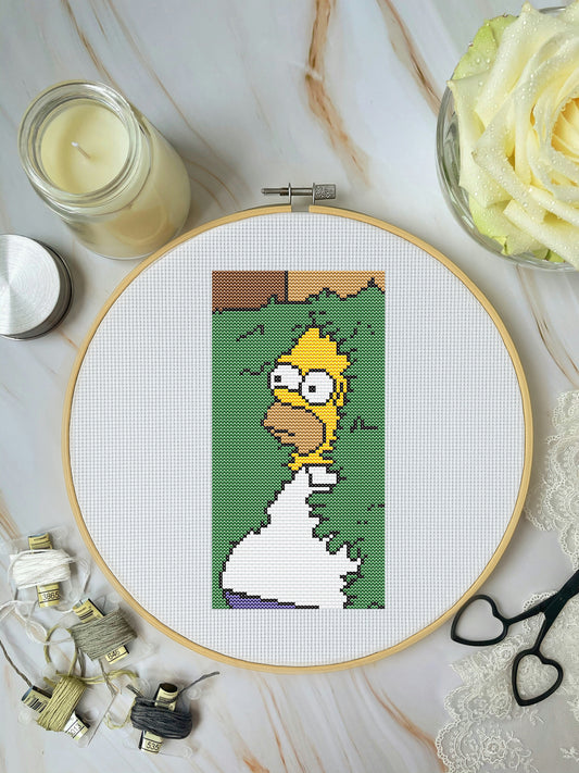 Cross-stitch pattern of a character in an embroidery hoop on a marble surface with a candle and flowers.