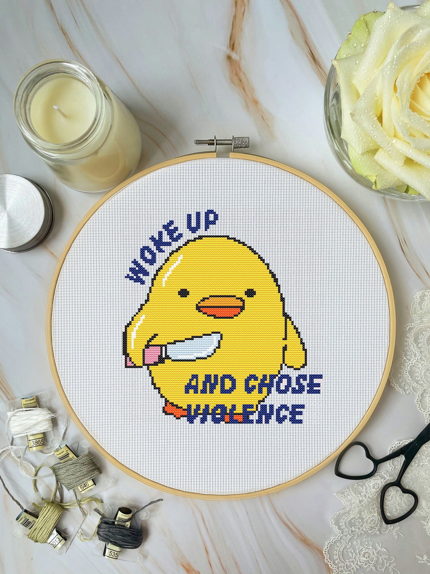 Cross-stitched design of a yellow character holding a knife with text 'Woke up and chose violence' on a white background.