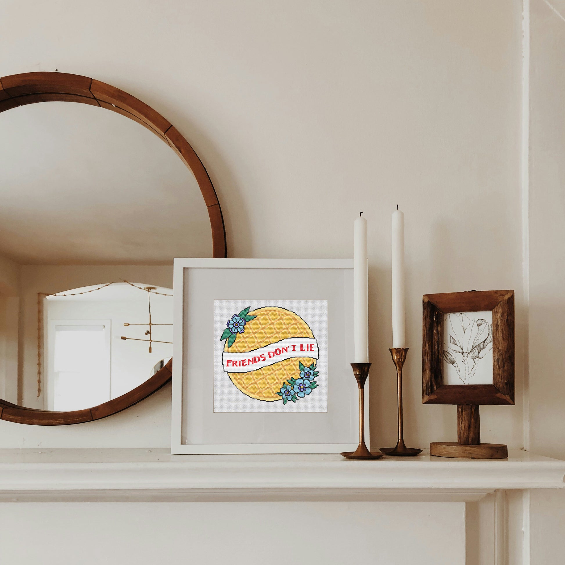 Framed artwork with 'Friends Don't Lie' quote on a shelf with candles and a mirror.