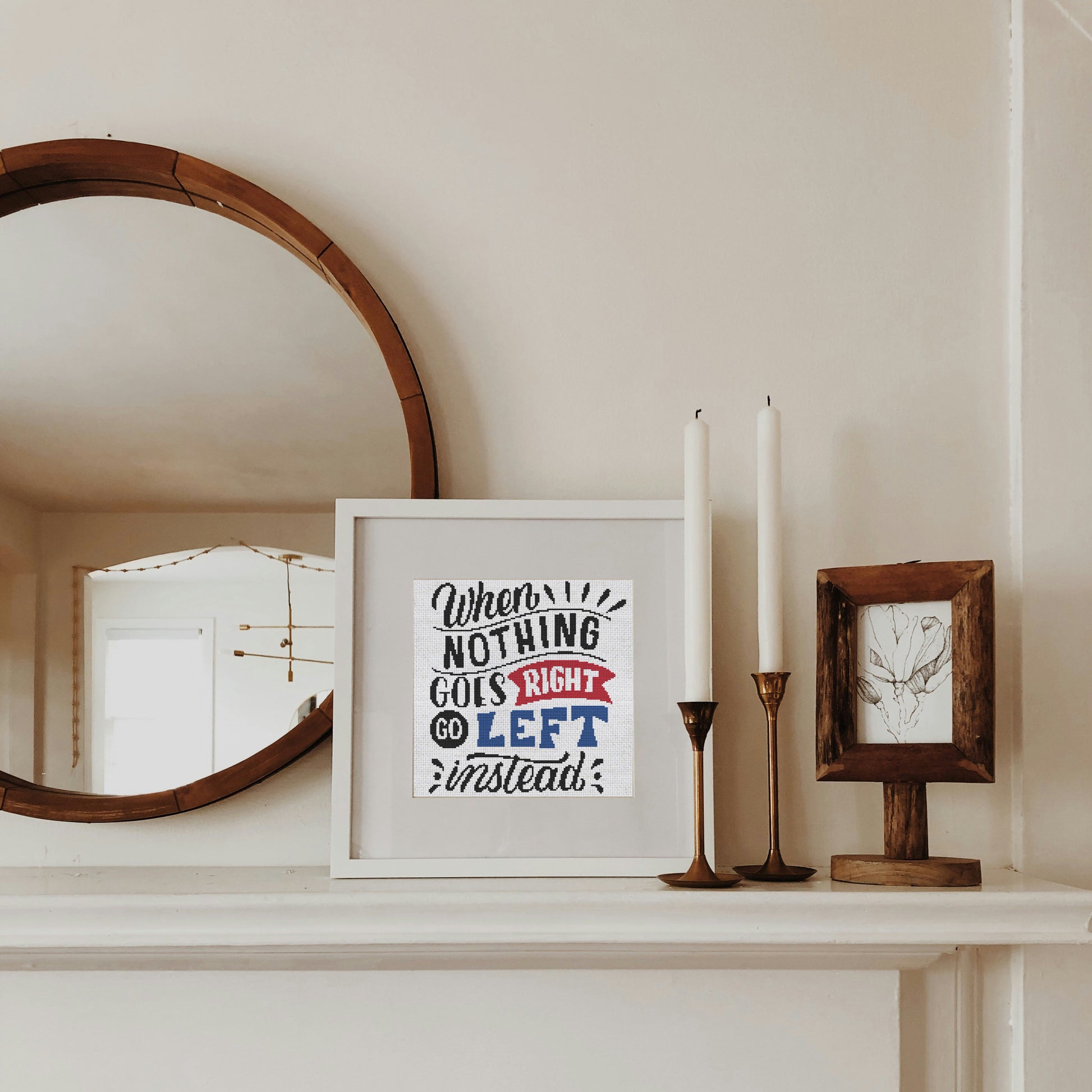 Framed artwork on a mantelpiece with candles and a mirror.