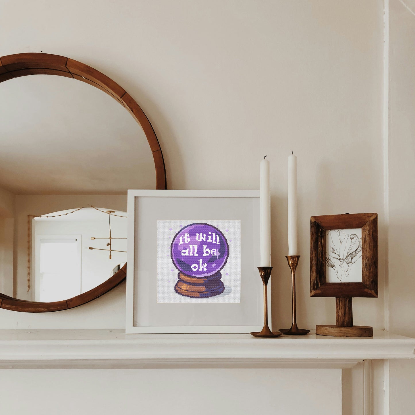 Framed artwork with motivational quote on a shelf next to candles and a mirror.