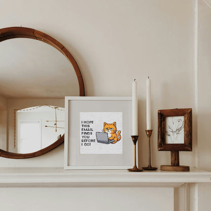 Framed picture of a cat with text on a shelf with candles and a mirror.