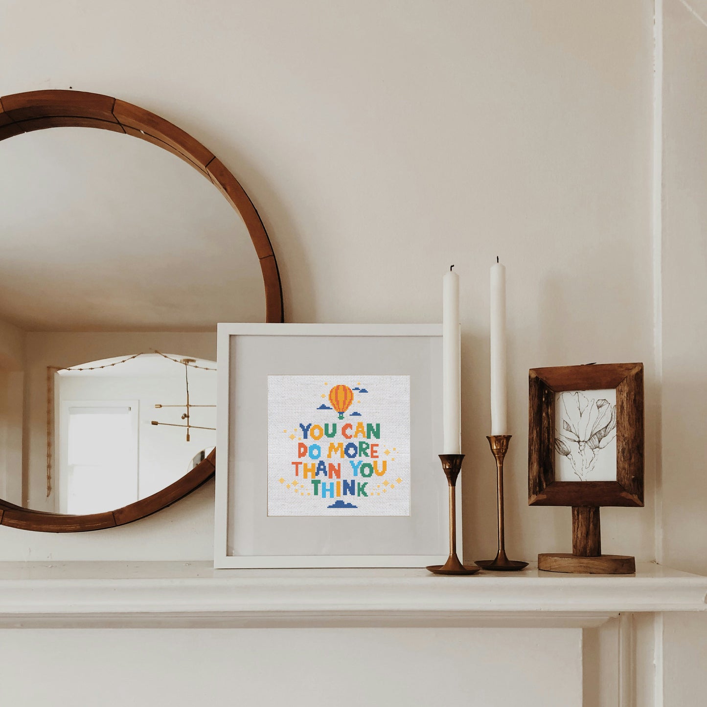 Decorative items on a mantelpiece including a framed print and candles.