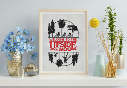 Framed artwork with 'Welcome to the Upside Down' text and silhouettes on a wall with decorative items.