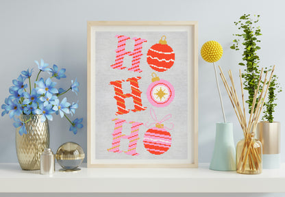 Framed cross-stitched art with 'Ho Ho Ho' and Christmas ornaments on a shelf with decorative items.
