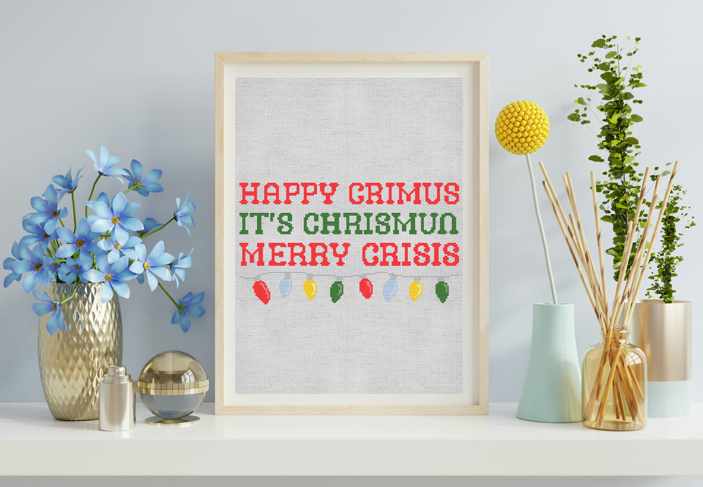 Framed print with 'Happy Grimus It's Chrismus Merry Crisis' text on a wall with decorative items.