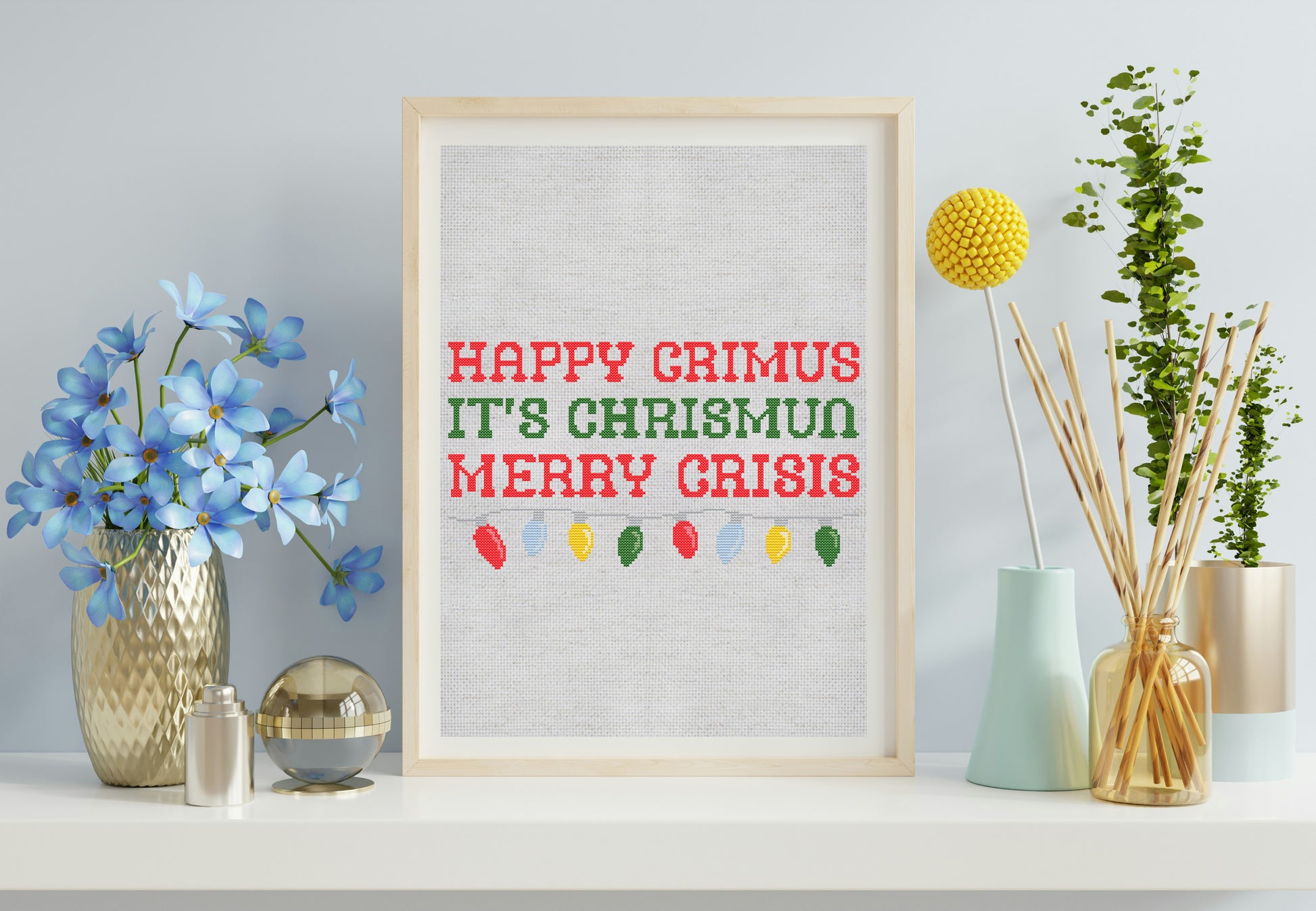 Framed print with 'Happy Grimus It's Chrismus Merry Crisis' text on a wall with decorative items.