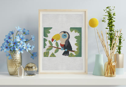 Framed cross-stitch art of a toucan on a shelf with decorative items.