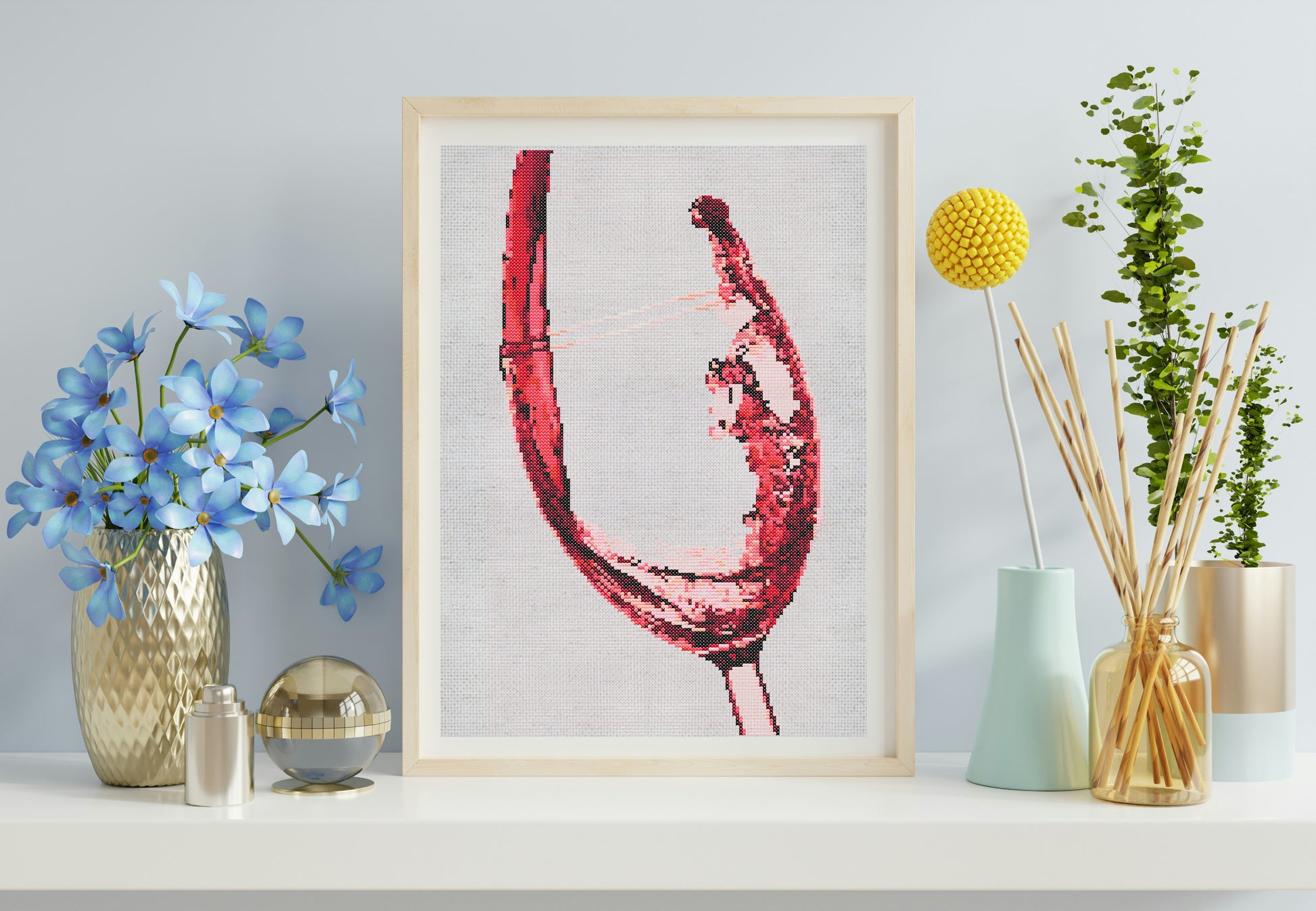 Framed artwork of a red wine glass on a shelf with decorative items.