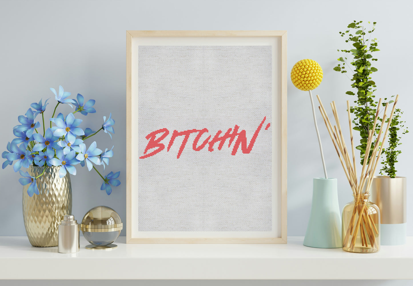 Framed artwork with the word 'BITCHIN'' on a shelf with decorative items.
