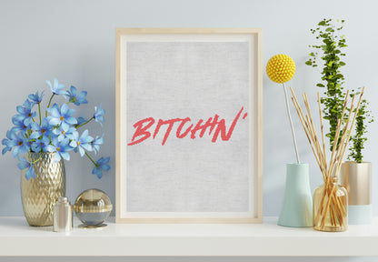 Framed artwork with the word 'BITCHIN'' on a shelf with decorative items.