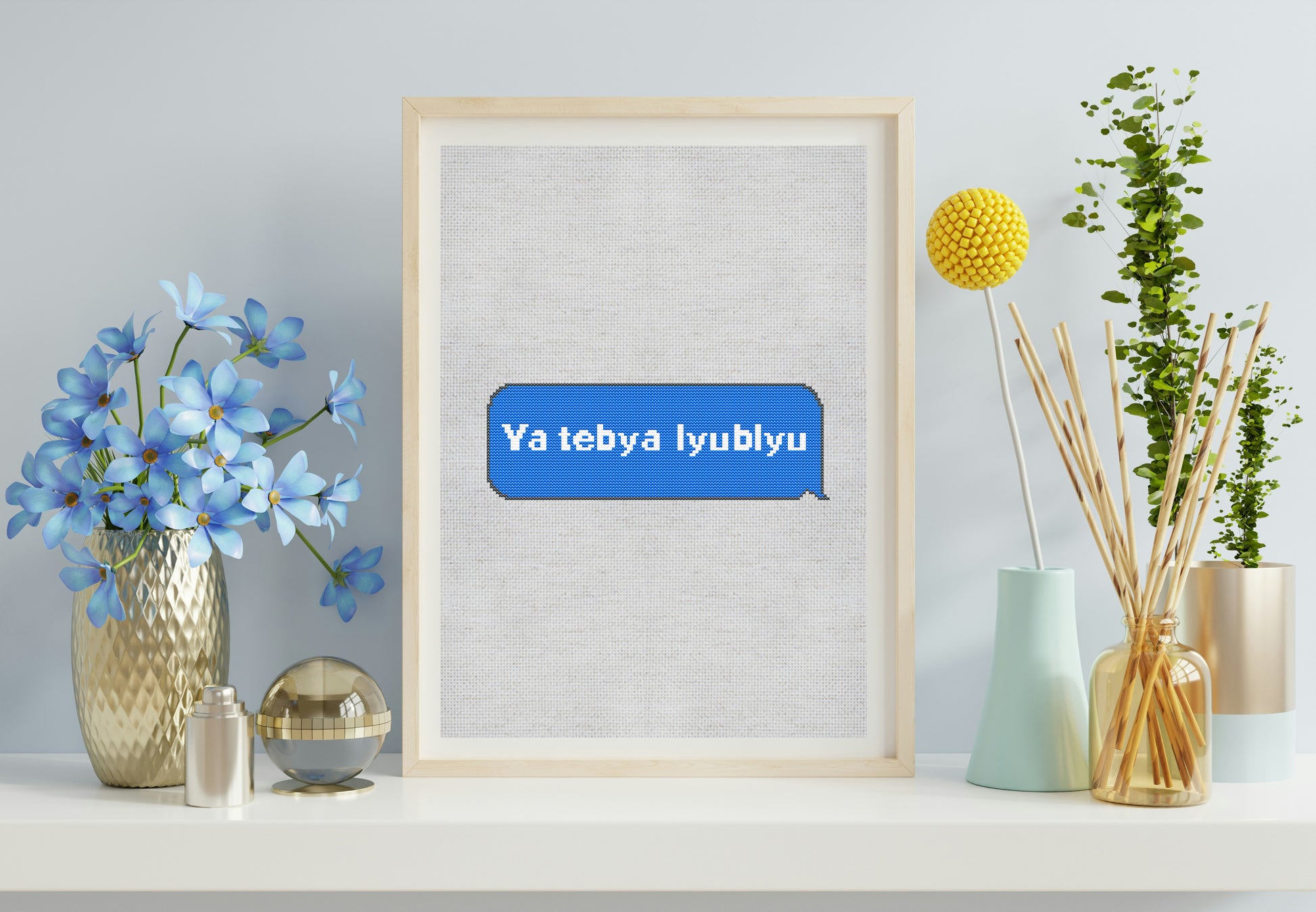 Framed artwork with 'Ya tebya lyublyu' text on a wall with decorative items.