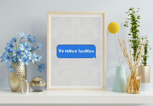 Framed artwork with 'Ya tebya lyublyu' text on a wall with decorative items.