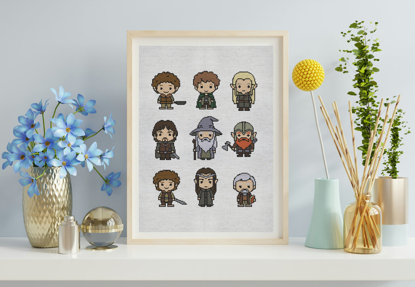 Framed cross-stitch art of characters on a wall with decorative items.