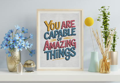 Framed motivational poster with 'You are capable of amazing things' text on a shelf with decorative items.