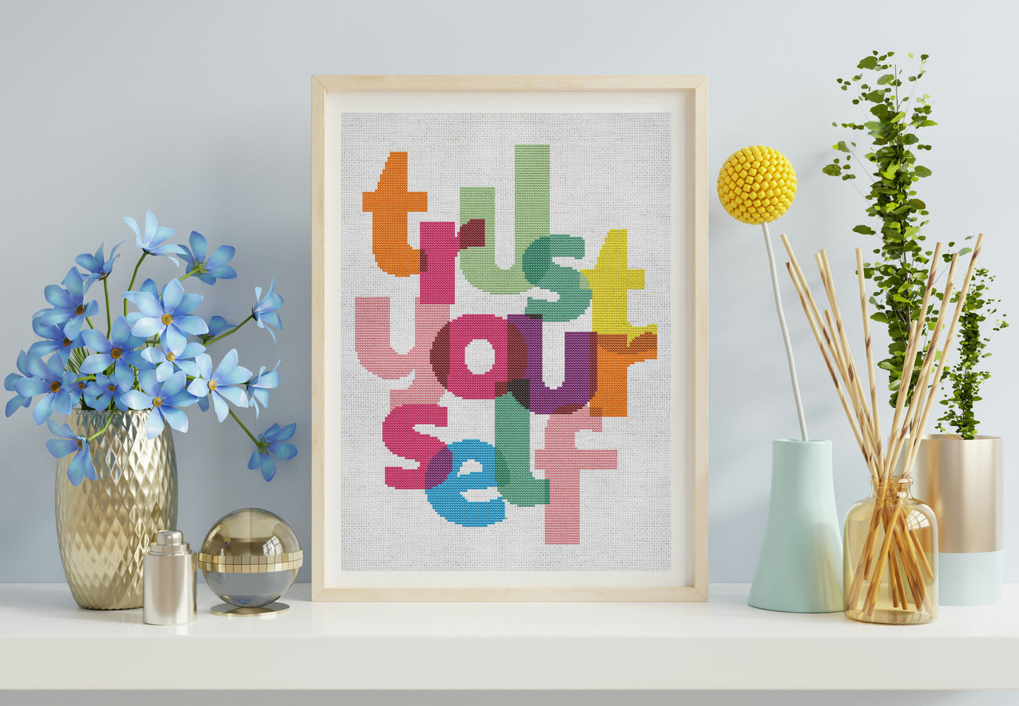 Framed artwork with colorful letters spelling 'Trust Yourself' on a shelf with decorative items.