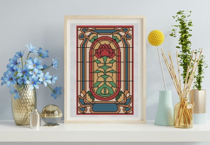 Decorative stained glass-style artwork with a rose design in a wooden frame, placed on a shelf with decorative items.