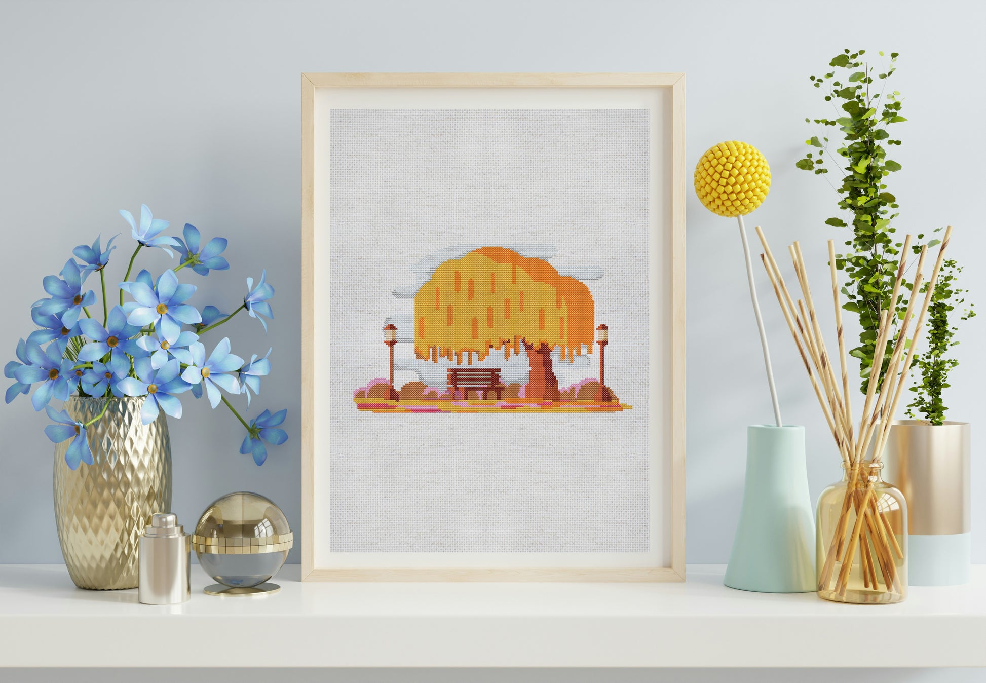 Framed artwork of a tree with a bench on a wall with decorative vases and plants.