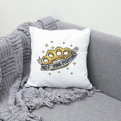 White pillow with a gold knuckle duster design and text on a gray couch.