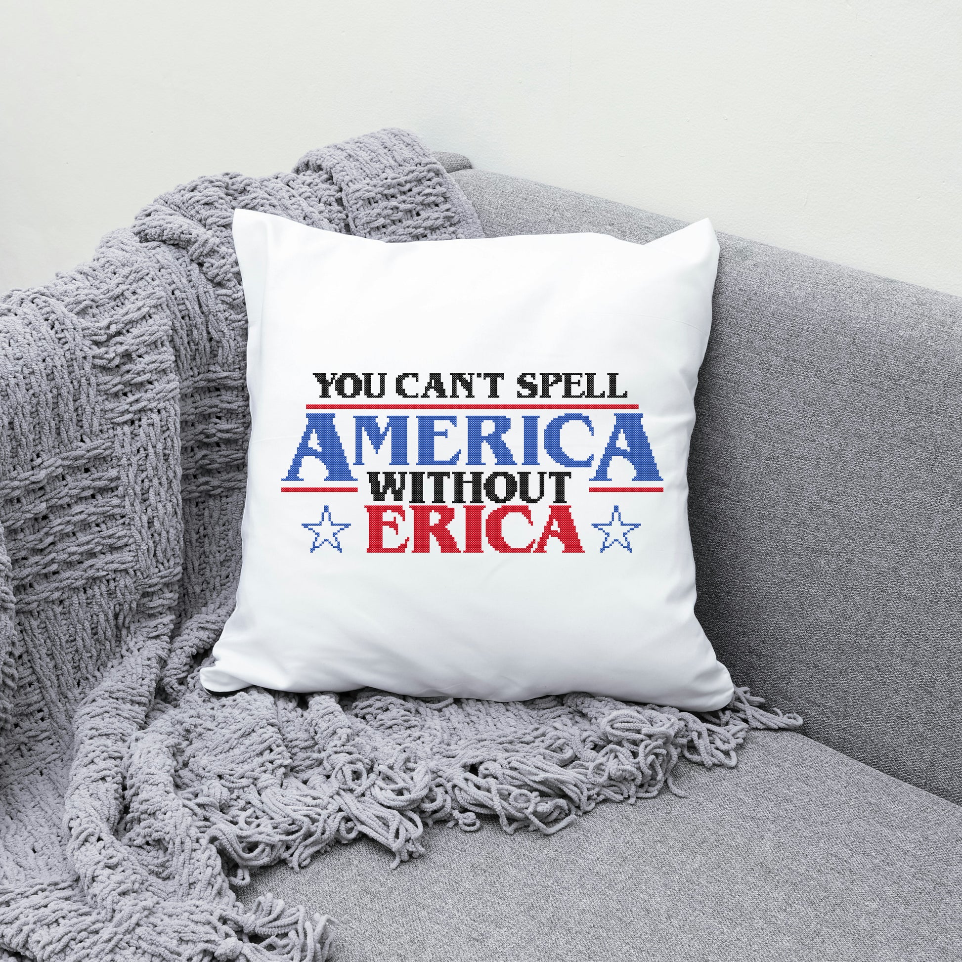 White pillow with text 'You can't spell America without Erica' on a gray couch.