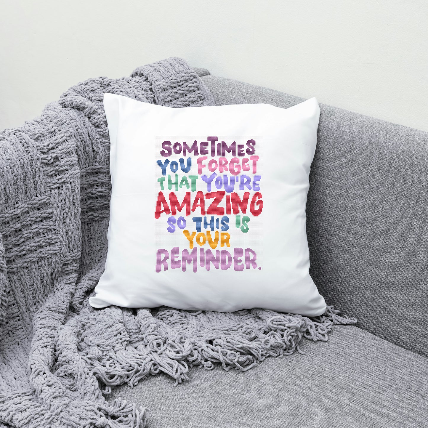 White pillow with colorful text on a gray couch