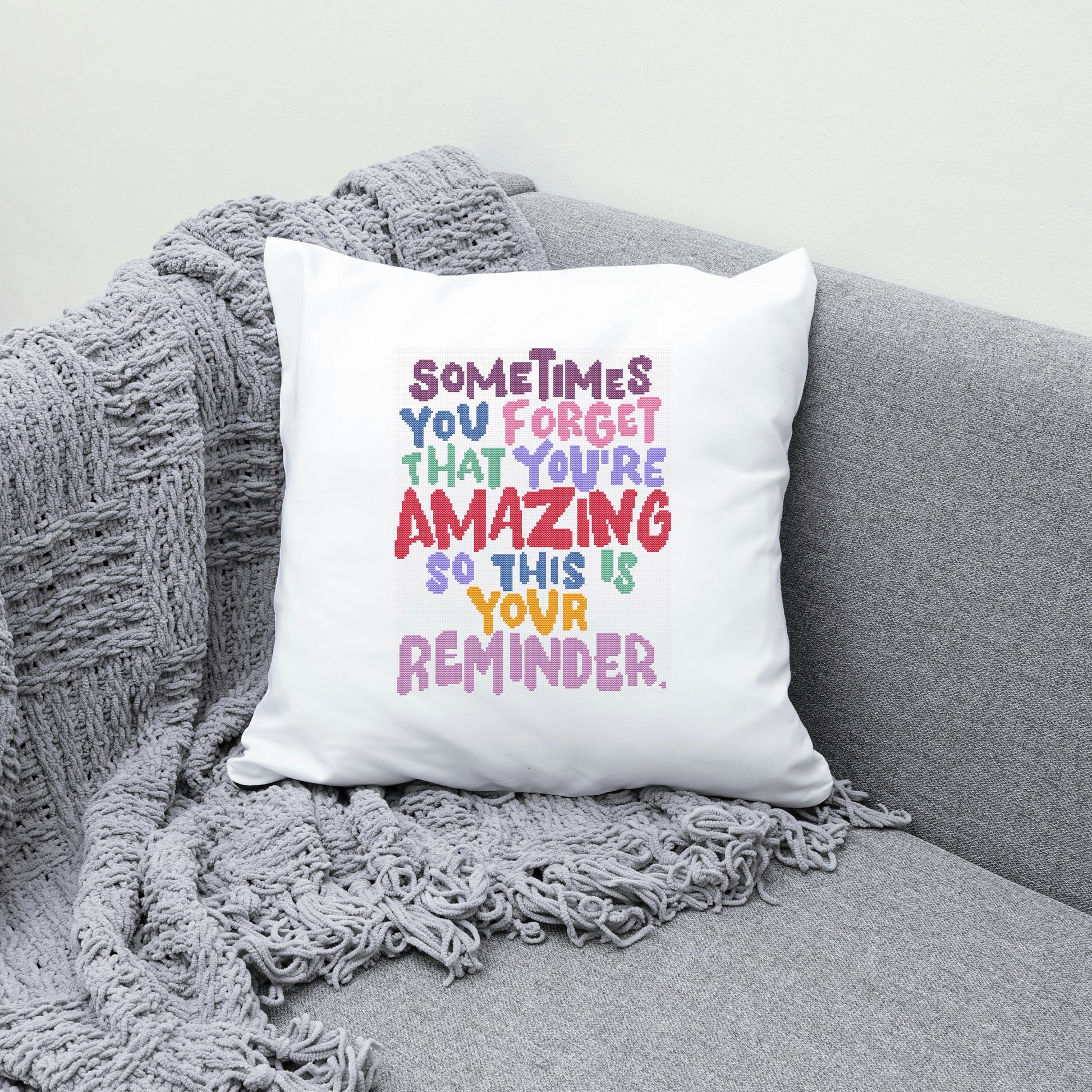 White pillow with colorful text on a gray couch