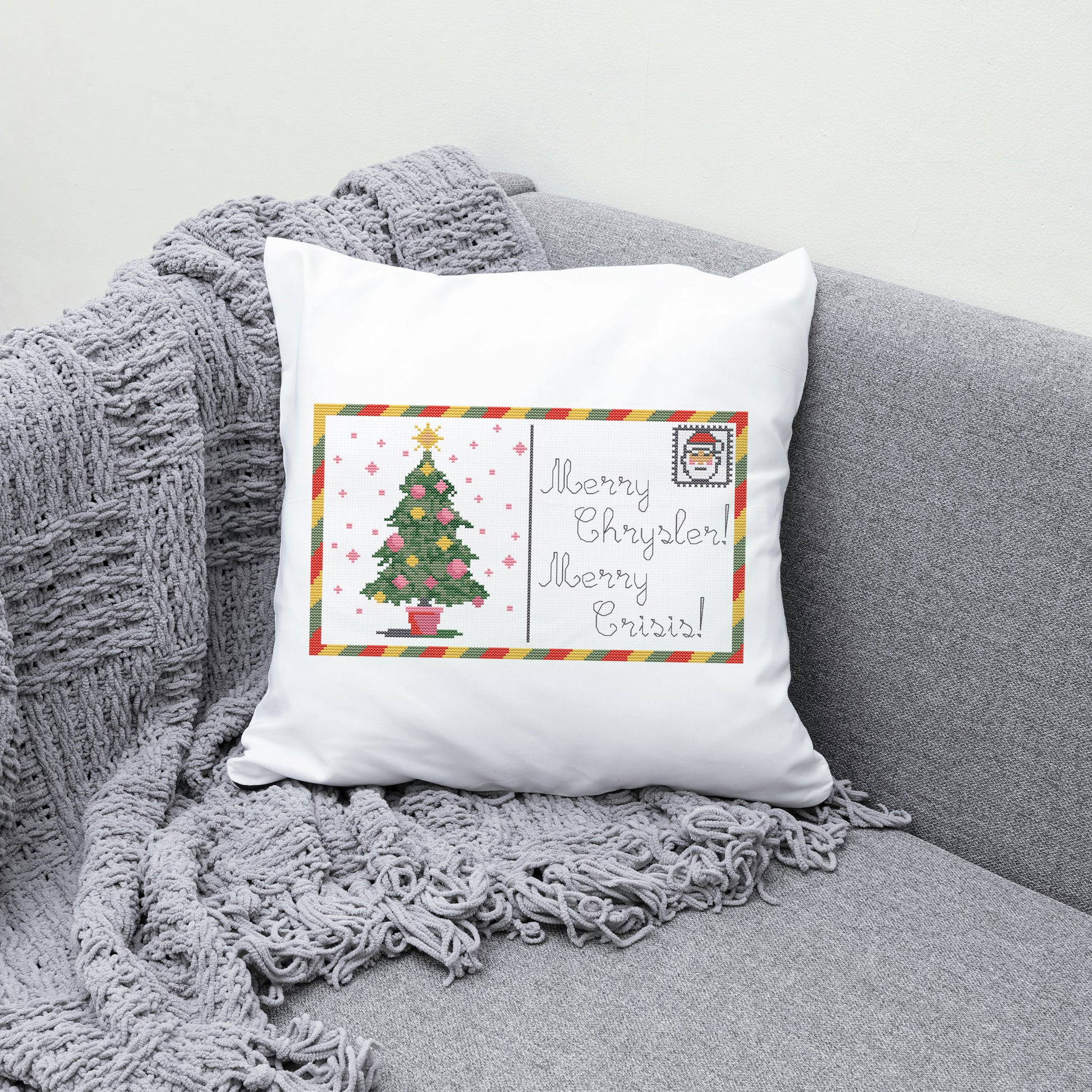 Decorative pillow with Christmas tree design and text on a gray couch.