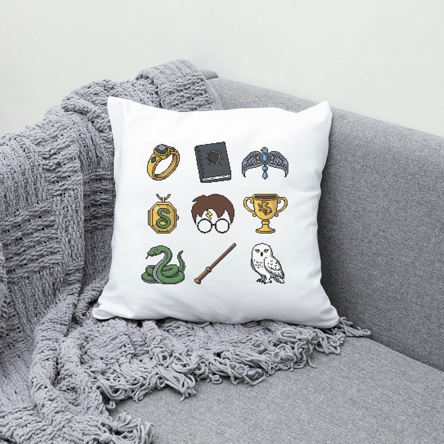Decorative pillow with Harry Potter-themed illustrations on a gray couch.