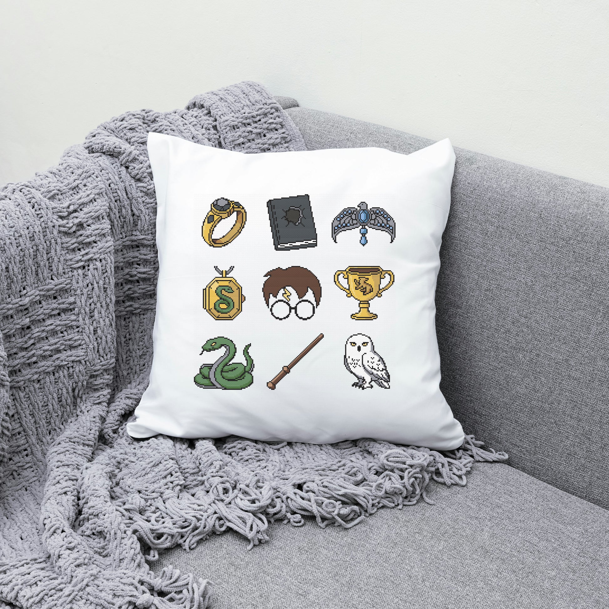 Decorative pillow with Harry Potter-themed illustrations on a gray couch.