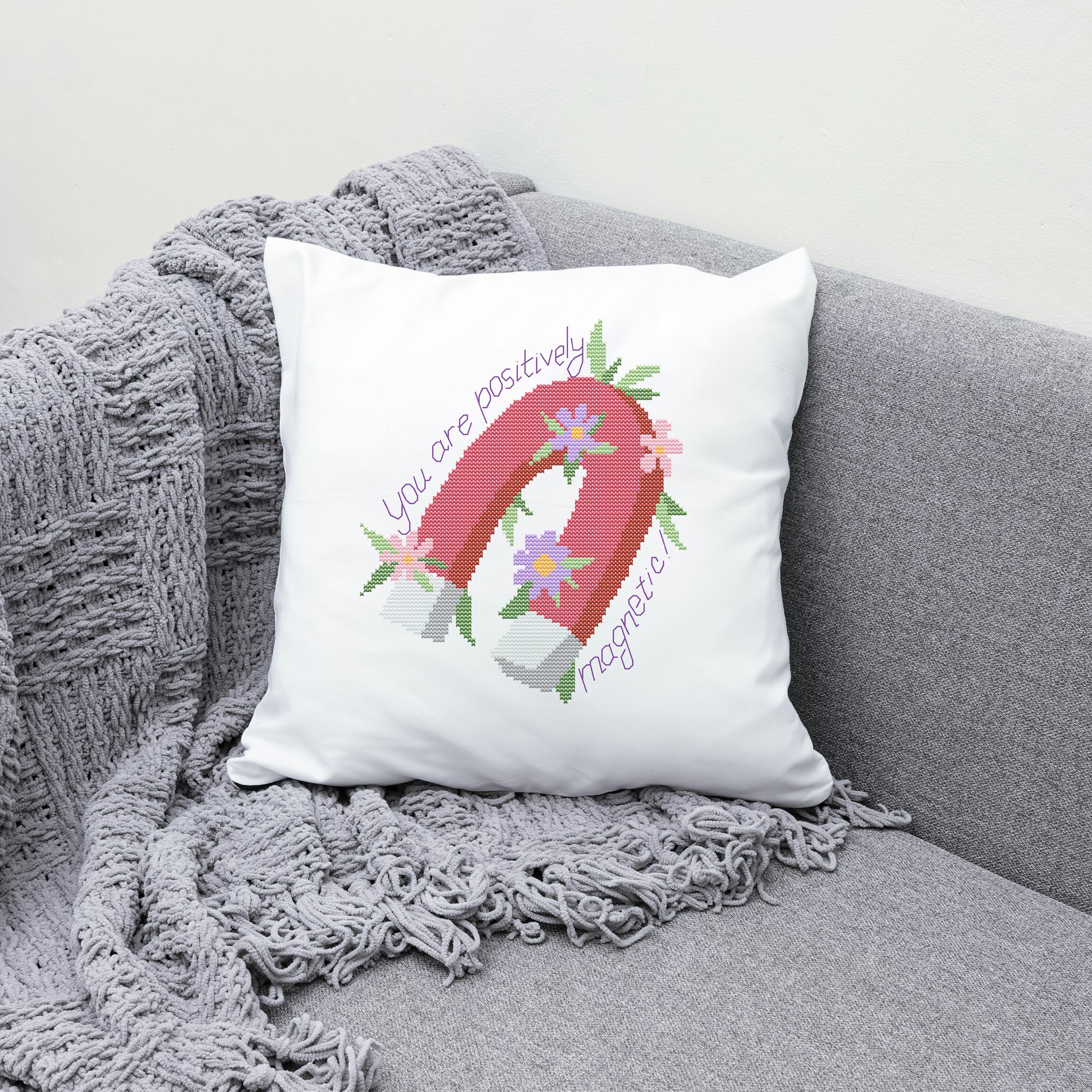 Decorative pillow with a pink letter 'A' and text on a gray couch.