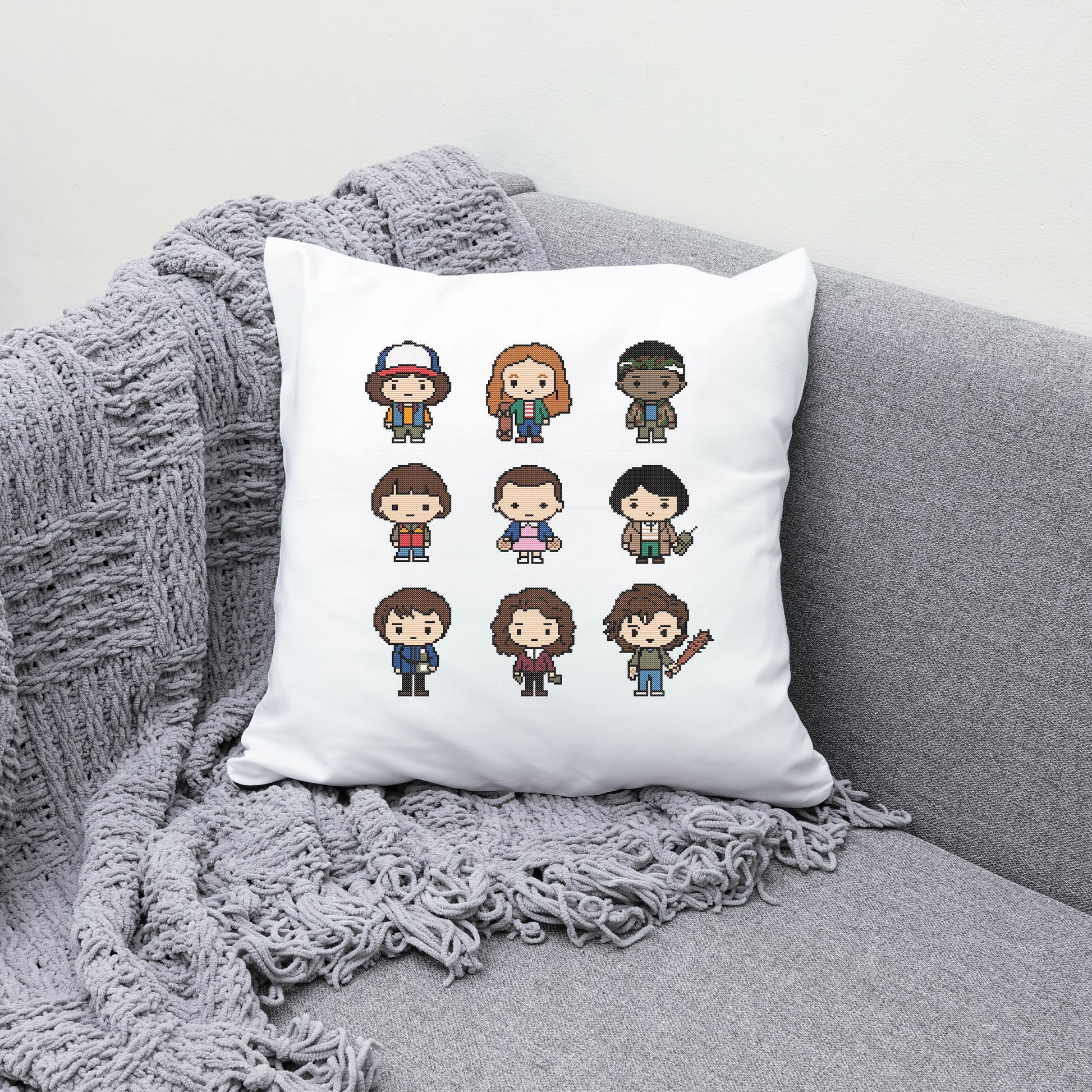 White pillow with pixel art character designs on a gray couch