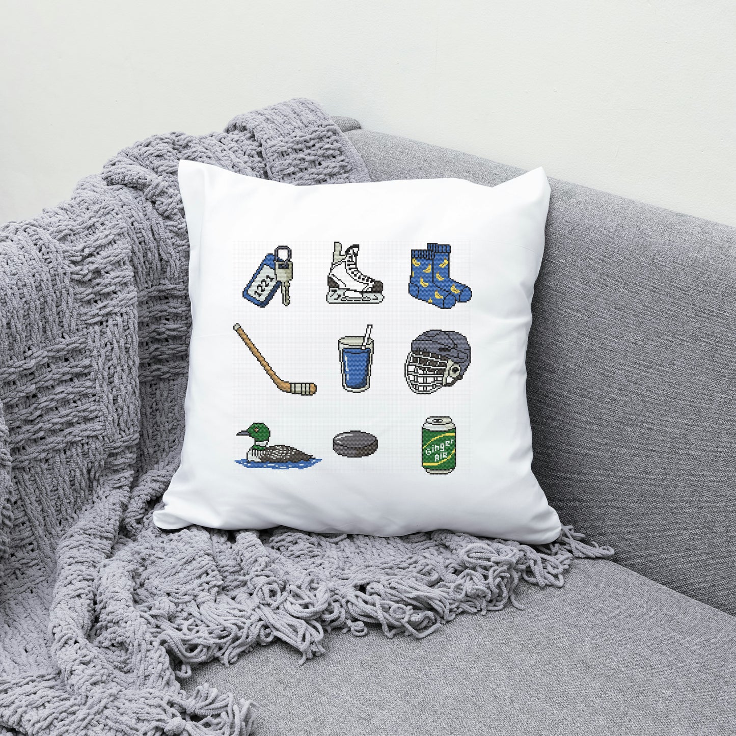 Decorative pillow with hockey-themed illustrations on a gray couch.