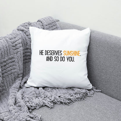 White pillow with text on a gray couch with a blanket