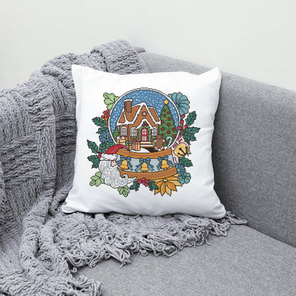 Decorative pillow with a Christmas design featuring a house, trees, and a gnome on a gray couch.