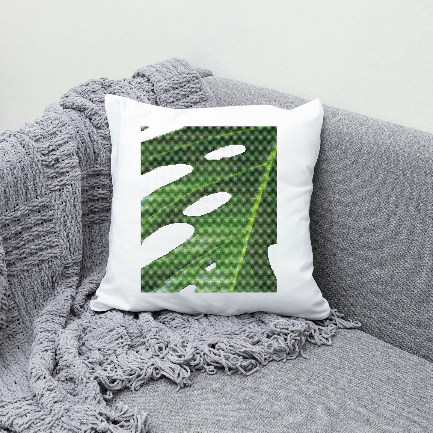 Decorative pillow with a leaf pattern on a gray couch