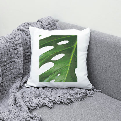 Decorative pillow with a leaf pattern on a gray couch