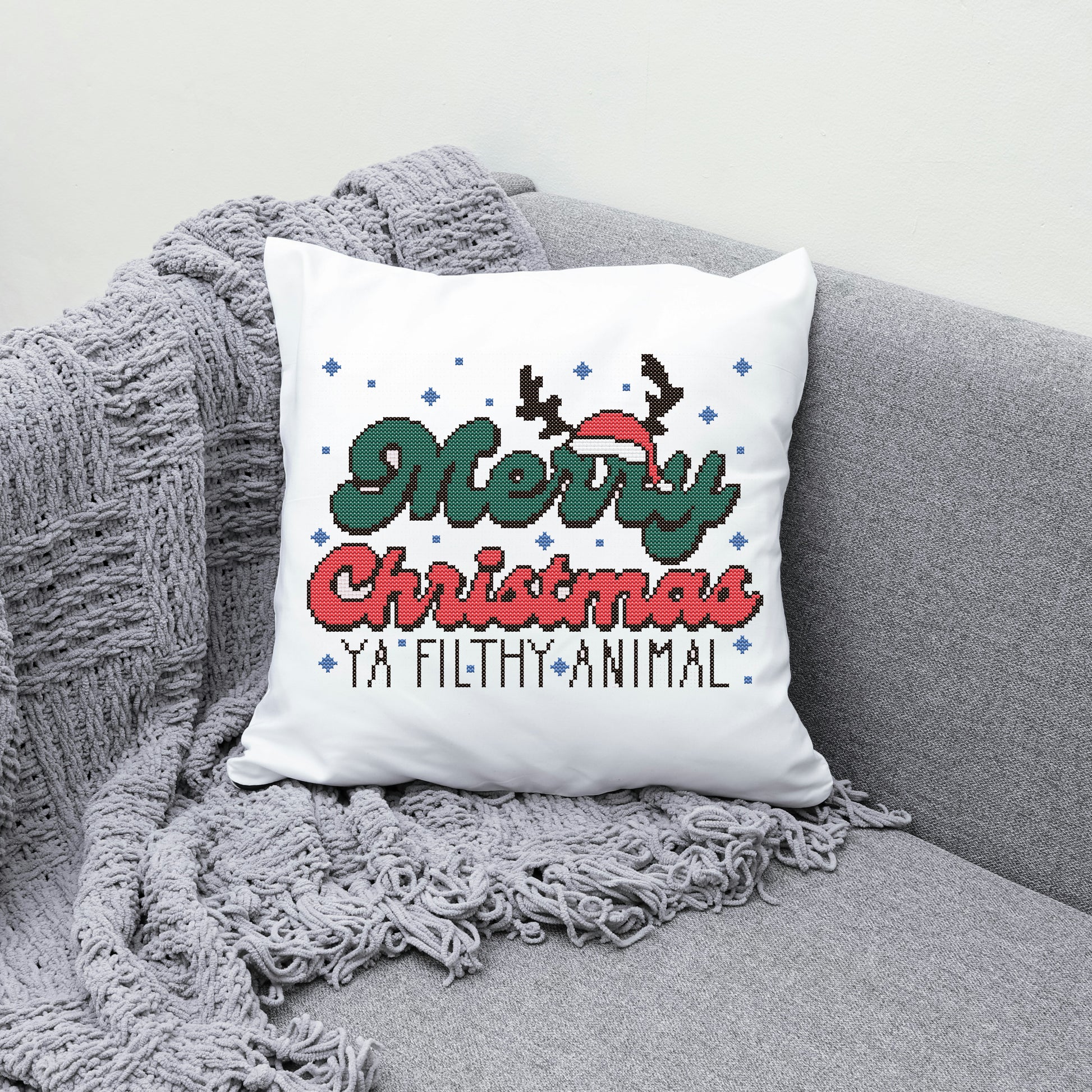 White pillow with Christmas-themed text on a gray couch