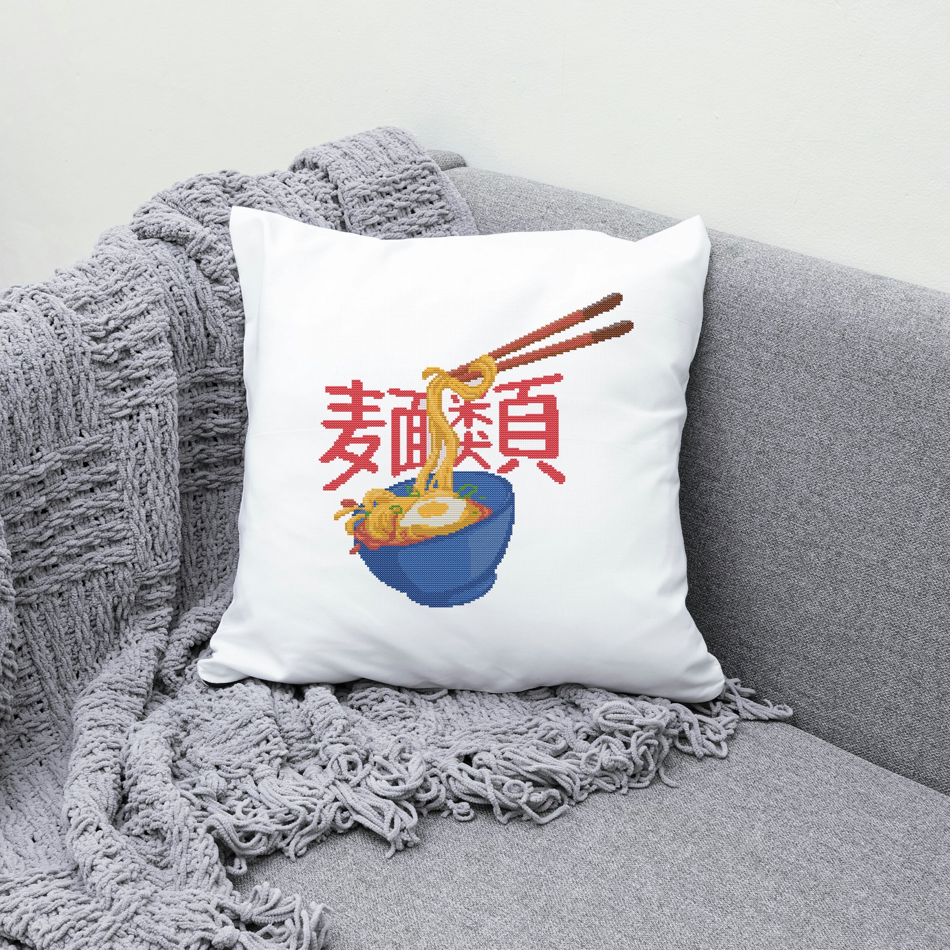 White pillow with a bowl of ramen design on a gray couch