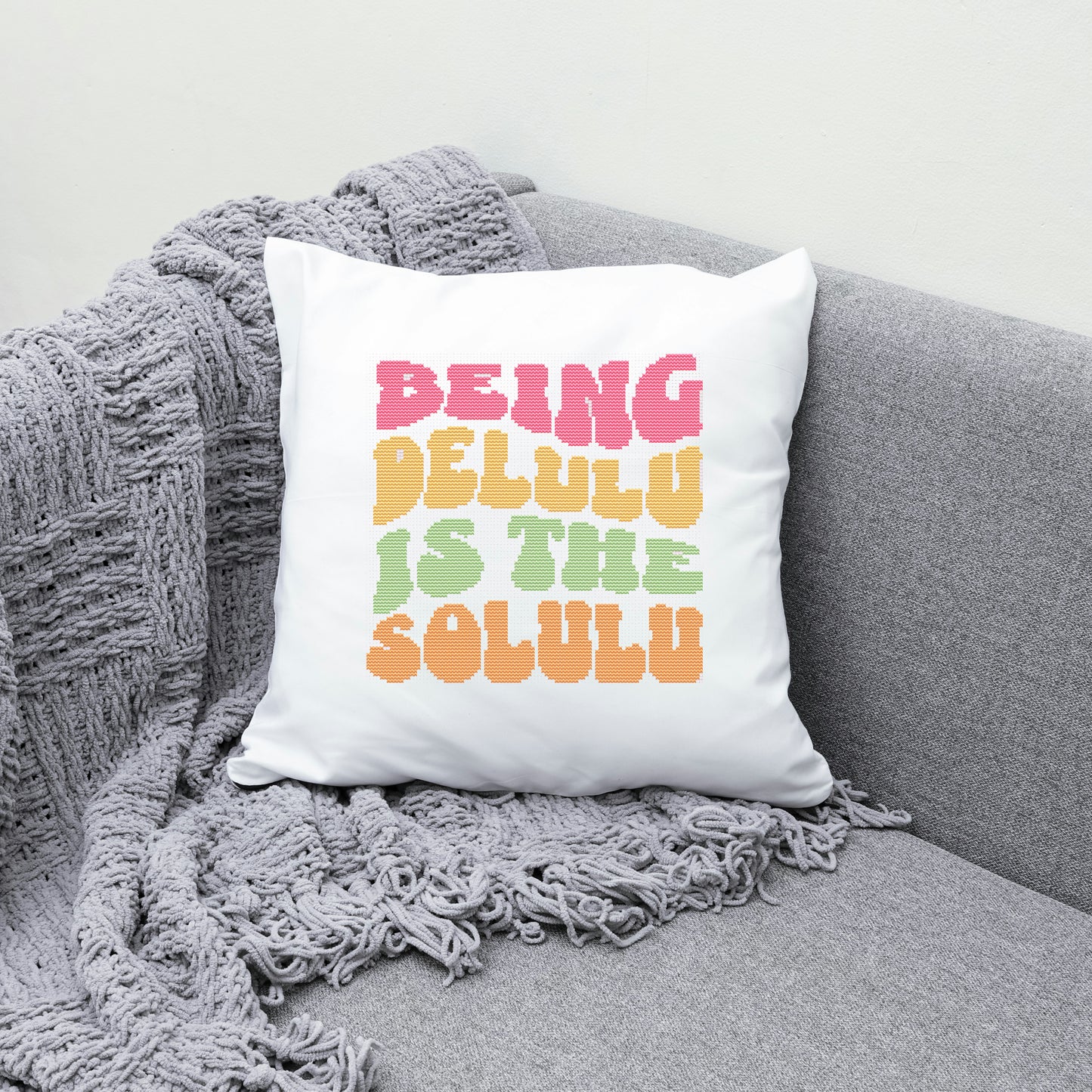 White pillow with colorful text on a gray couch