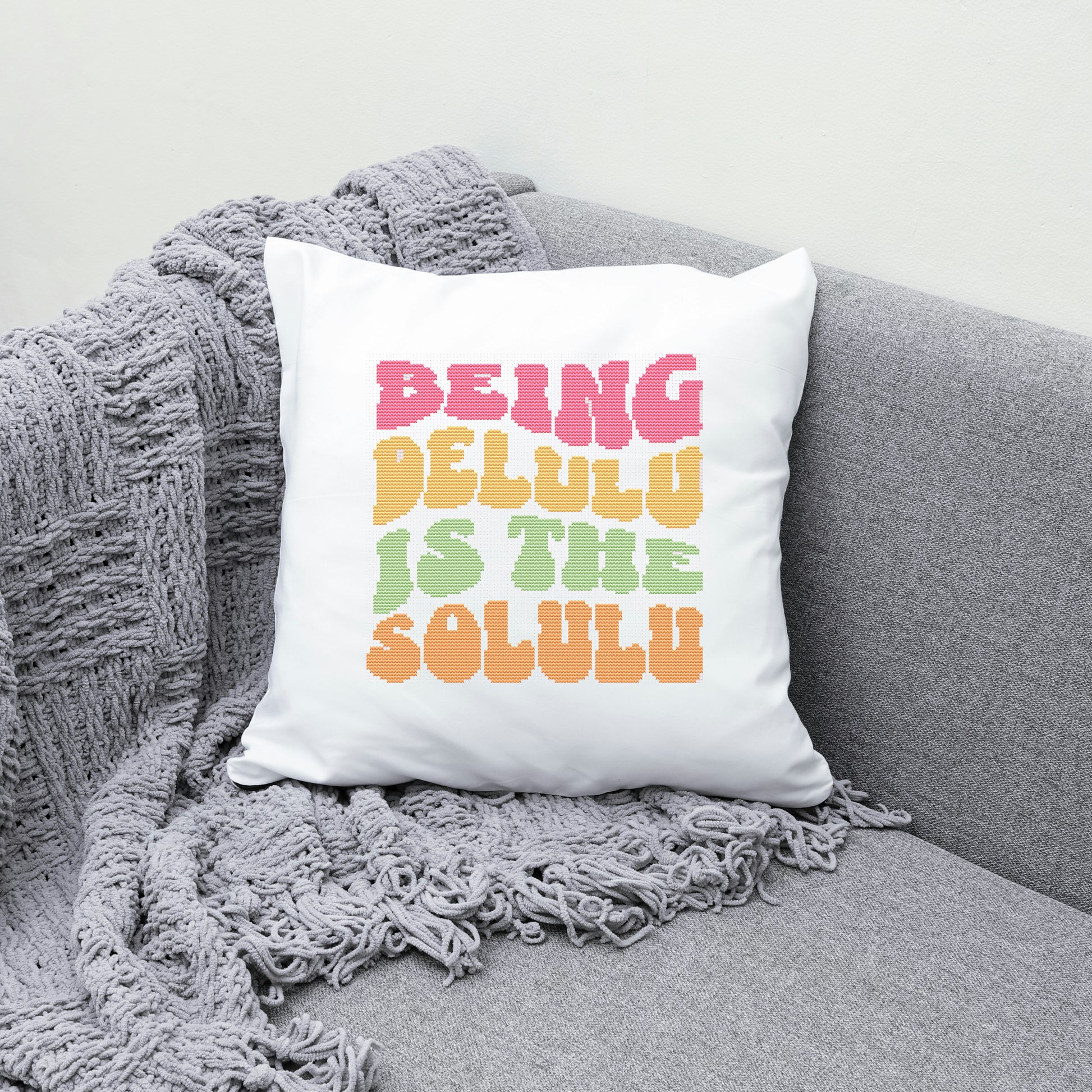 White pillow with colorful text on a gray couch