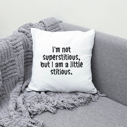 White pillow with humorous text on a gray couch with a textured blanket.